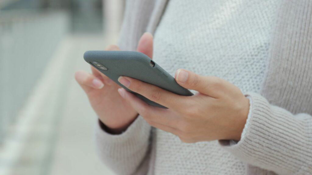 Woman with gray sweater holding a mobile phone