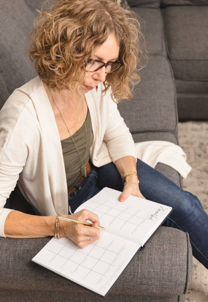 Lady sitting on couch writing about how to declutter and not get organized.