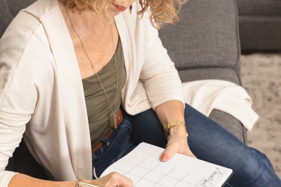 Lady sitting on couch writing about how to declutter and not get organized.