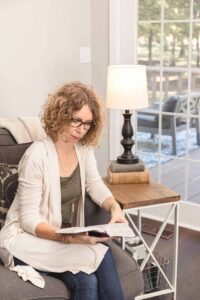 Lady sitting on couch reading bible and learning about types of motivation.