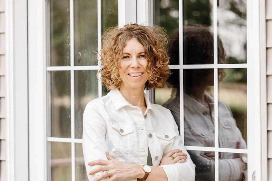 Woman standing by French Doors thinking about the types of motivation and how they influence our habits.