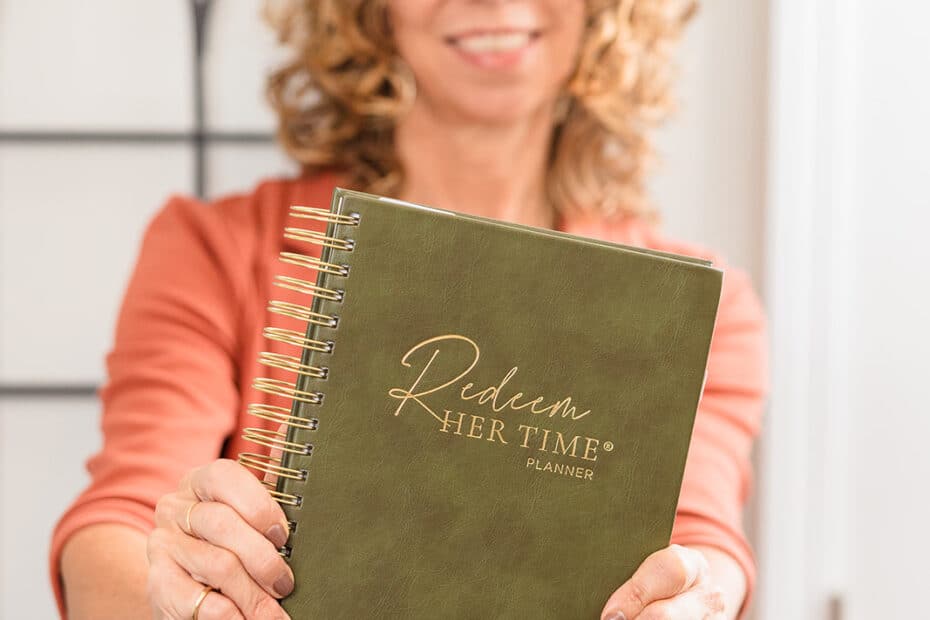 A lady holding the Redeem Her Time Planner to start stewarding her time.