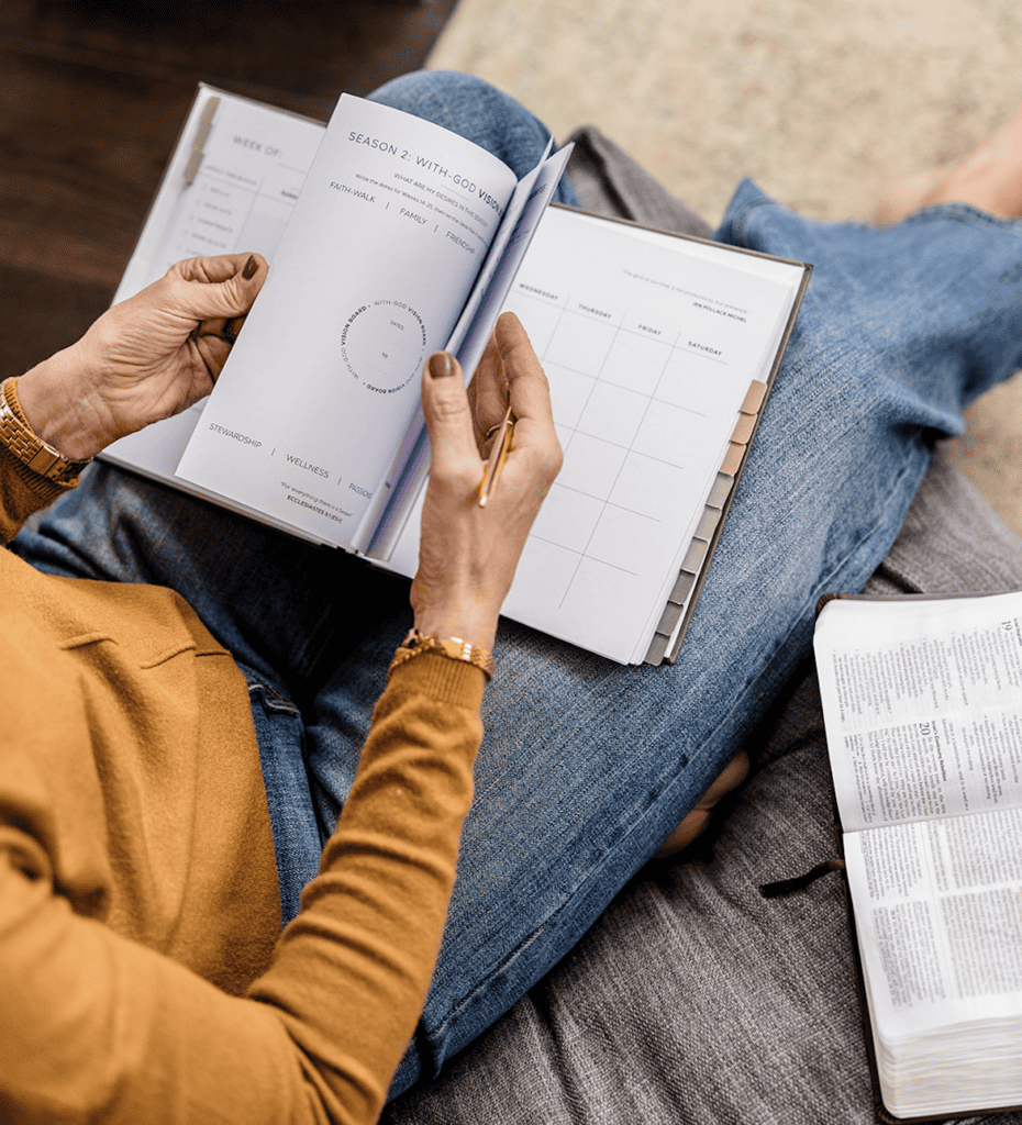 Lady sitting on a chair flipping through her Redeem Her Time Planner learning annual planning with God.