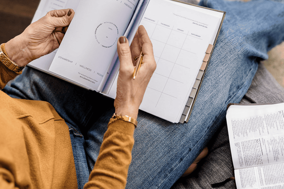 Lady sitting on a chair flipping through her Redeem Her Time Planner learning annual planning with God.