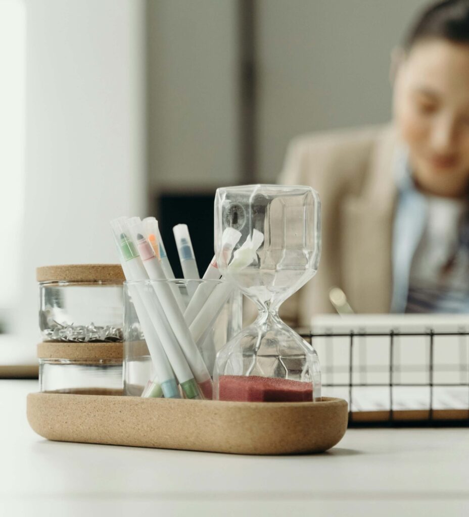 Minimalist desk setup with pens, hourglass timer, and jars for office supplies