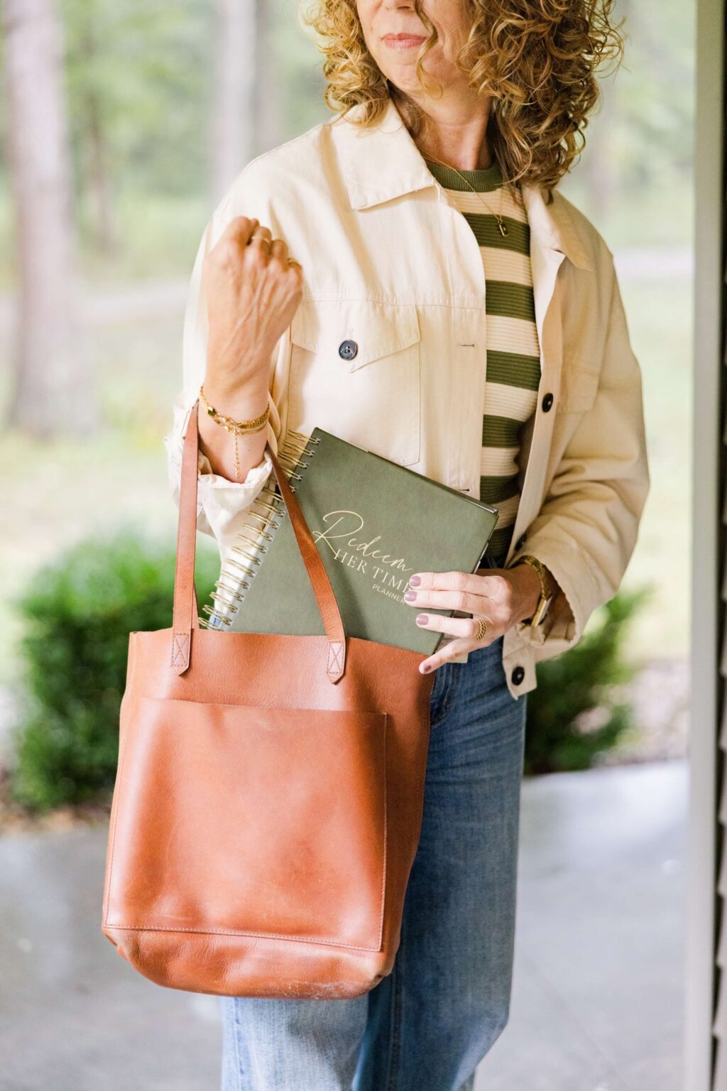 Christian time coach holding Redeem Her Time planner with a leather tote bag